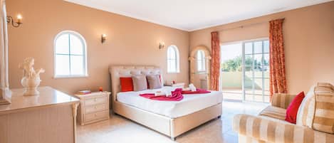 A spacious bedroom with a large bed, a bedside table, a dresser, and a chair.