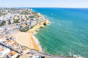 Luftaufnahme einer Küstenstadt mit Strand, Gebäuden und Klippen.