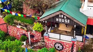 Un edificio con techo verde y un letrero que dice '80's HOUSE'.