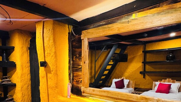 Una habitación con cama, ventana y vista a una escalera, además de una pared con textura.