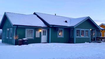 En enplansbyggnad med ett sadeltak, en ytterdörr och fönster.
