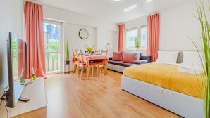 Quarto moderno com cama, sofá, área de refeições e televisão.