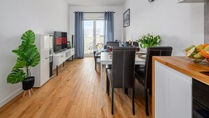 A modern apartment with a dining area, a living room with a TV, and a balcony with curtains. - Beautiful Seaview Flat in Stagadon Island (Łódź)
