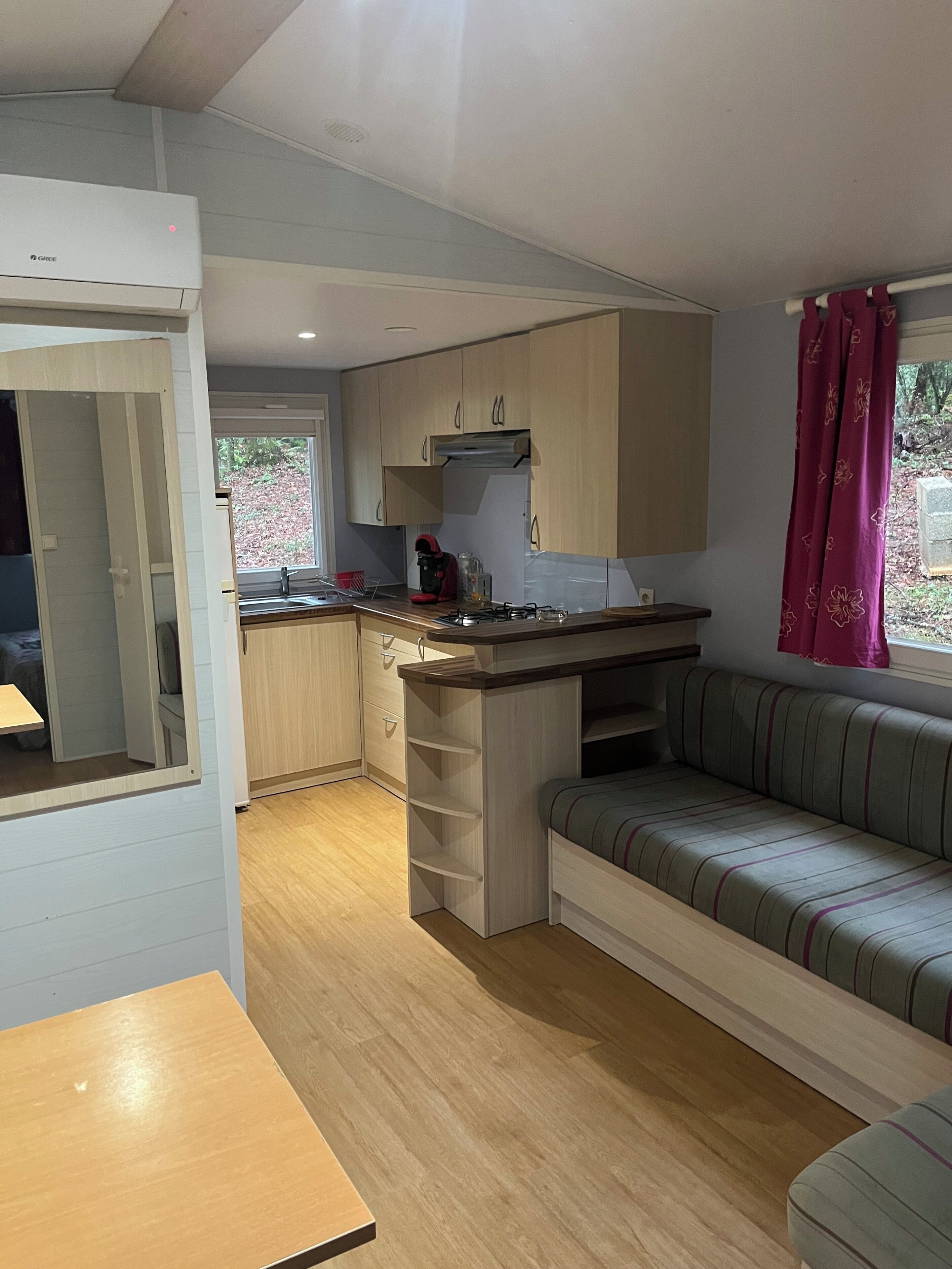 A compact kitchen with a gas stove, a sink, and a window. There is a sofa and a small table in the living area.