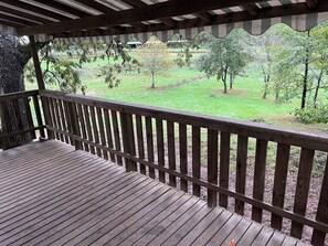 A wooden deck with a railing overlooking a grassy area with trees. - A quiet mobile home surrounded by nature (Gavaudun)