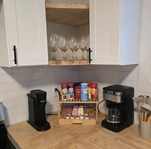 Eine Küche mit Kaffeemaschine, einer Gewürzregal und einem Schrank mit Weingläsern.