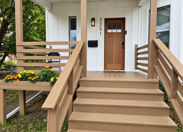 A wooden staircase leading to a front door with a mailbox and a number above it.