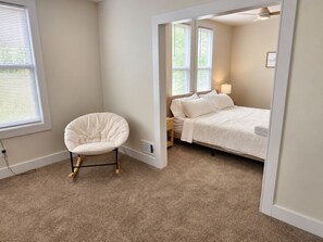 A bedroom with a single bed, a chair, and a window with blinds.