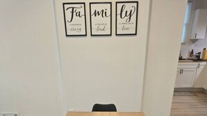 A dining area with a wooden table, black chairs, and a woven placemat. Three framed inspirational quotes hang on the wall above the table. - Spacious 5-bedroom house in awesome Detroit with AC (Detroit)