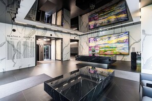 A modern lobby with a marble floor, a glass coffee table, and a large abstract painting. - Lush Home Near Varso Tower (Warsaw)