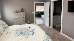 Ein Schlafzimmer mit Bett, Kommode und einer Tür zu einem Badezimmer.