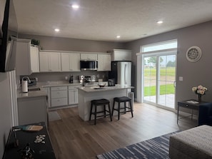 A modern kitchen with white cabinets, stainless steel appliances, and a central island with stools.