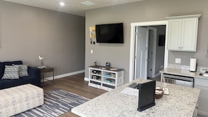 Ein modernes Wohnzimmer mit einem dunkelgrauen Sofa, einem Couchtisch und einem an der Wand befestigten Fernseher.
