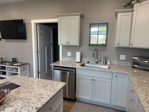 A modern kitchen with granite countertops, stainless steel appliances, and white cabinetry.