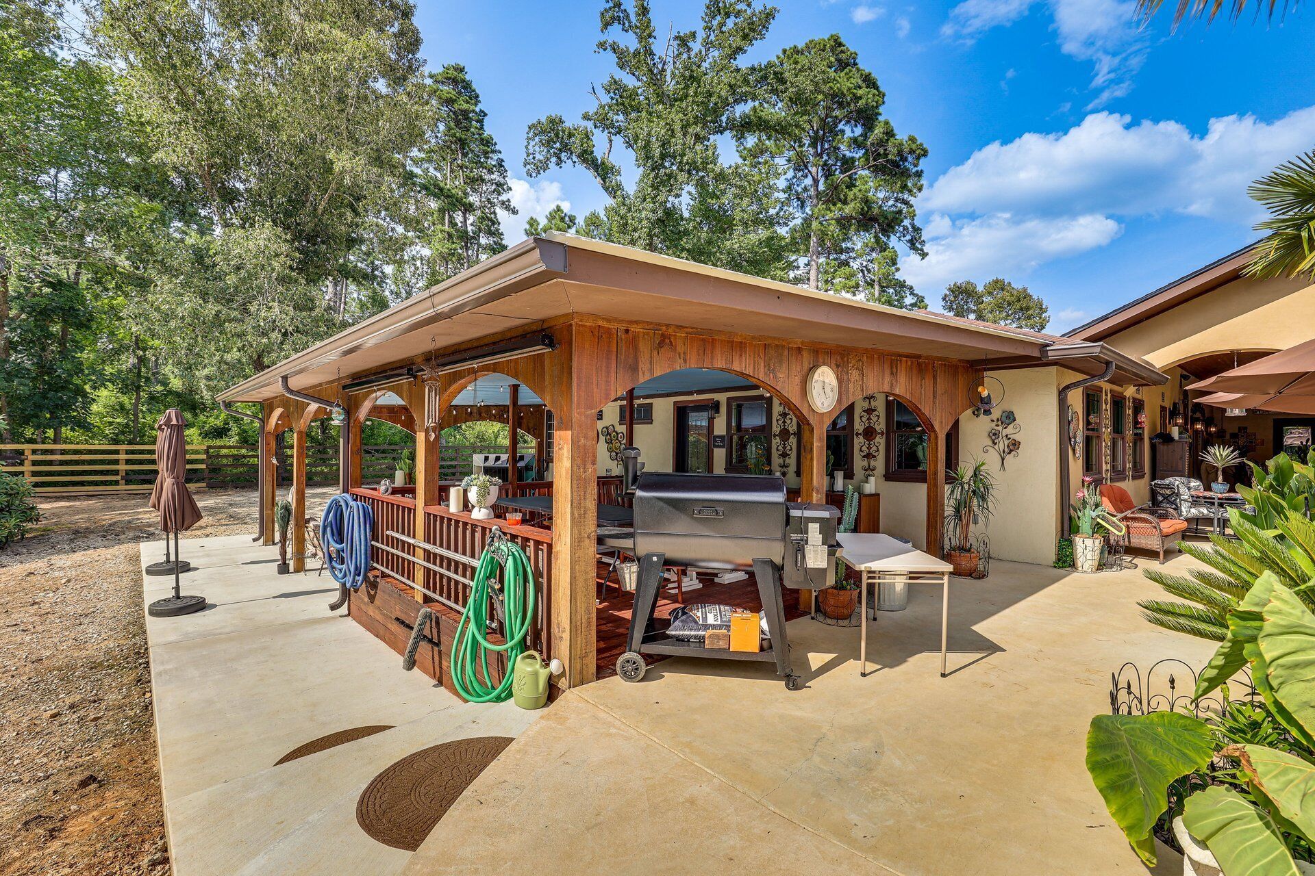 Un patio esterno coperto con un barbecue, posti a sedere e un recinto in legno.