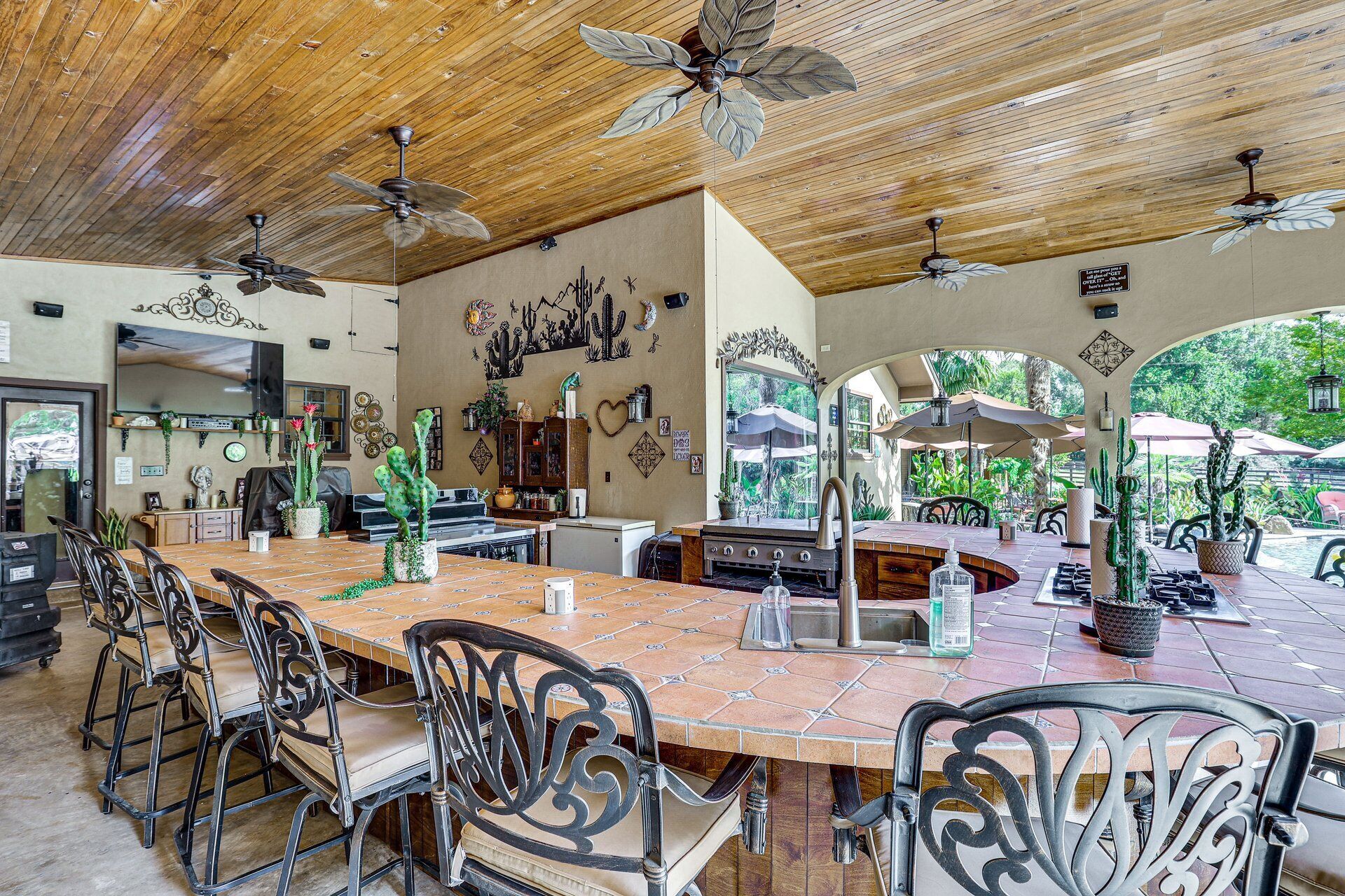 Un comedor amplio con una mesa larga, sillas, ventiladores de techo y vistas al exterior.