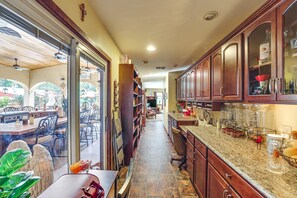 A kitchen with wooden cabinets, a granite countertop, and a dining area with a glass door leading outside.
