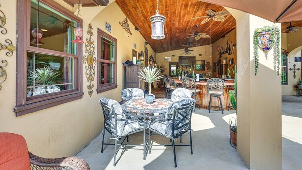 Une terrasse extérieure avec une table ronde et des chaises, un ventilateur de plafond et un plafond en bois.