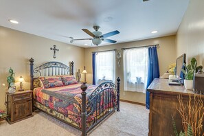 A bedroom with a bed, a desk, a ceiling fan, and a window with curtains.