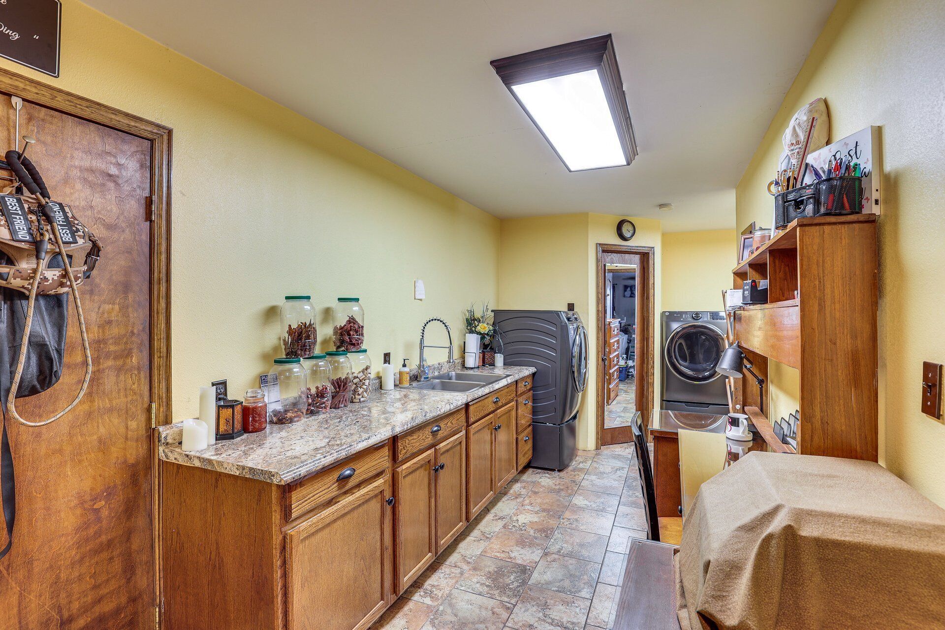 Una cucina compatta con mobili in legno, un piano di lavoro in granito e lavatrice e asciugatrice integrate.