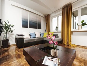 Una sala de estar moderna con un sofá modular, una mesita de centro y un ventanal con cortinas.