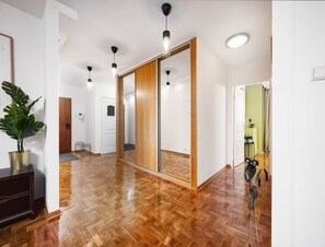 Un pasillo amplio con suelo de madera, un espejo grande y una planta en maceta.
