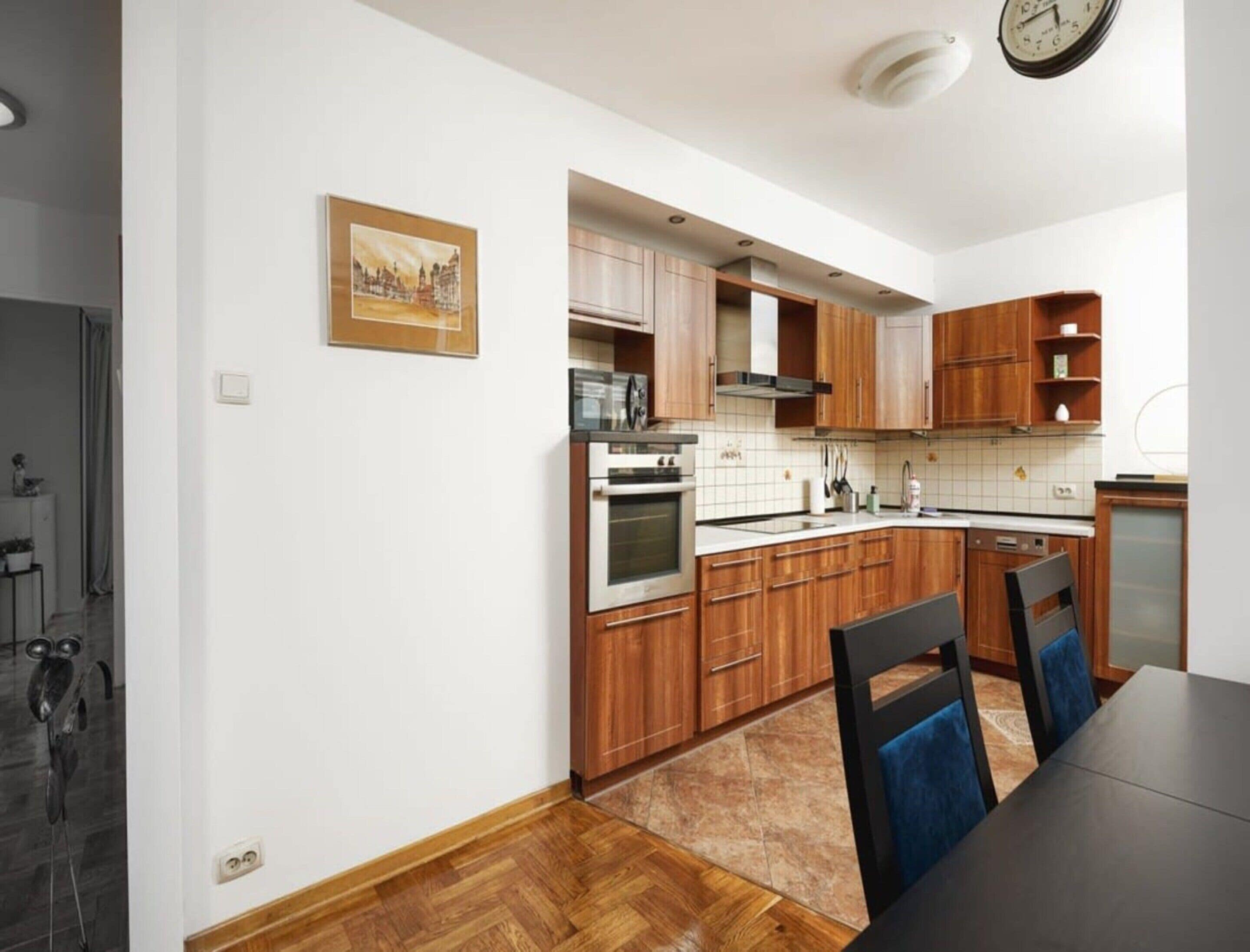 Eine moderne Küche mit Holzschränken, einem Einbauofen und einem Essbereich mit Tisch und Stühlen.