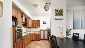 A modern kitchen with wooden cabinets, a built-in oven, and a dining area with a table and chairs. - Warsaw Home Near Center (Warsaw)