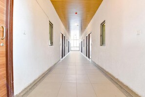 A long, narrow hallway with doors on both sides, leading to a bright room at the end.