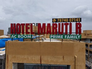 Placa de hotel com 'HOTEL MARUTI R' e 'AC ROOM' indicando quartos com ar condicionado.