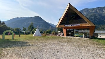 Un edificio moderno con tetto triangolare, con la scritta 'SCUOLA ITALIANA SCI & SNOWBOARD', sullo sfondo di montagne.
