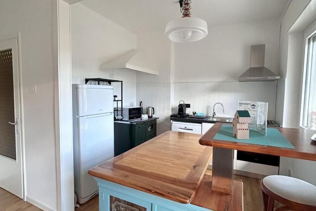 Una cucina compatta con isola in legno, un frigorifero bianco, un forno a microonde e un piano cottura.