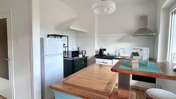 Una cucina compatta con isola in legno, un frigorifero bianco, un forno a microonde e un piano cottura.