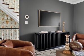 A modern living room with a black radiator, a framed artwork, and a stack of books on a console table. - Uptown Charlotte Luxury 4 bedroom Townhouse walkable to everything (Charlotte)