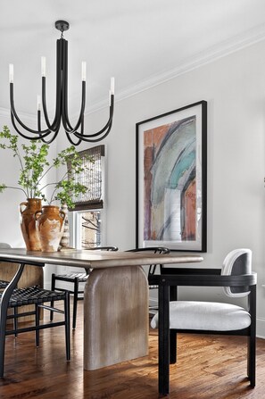 A dining area with a wooden table, black chairs, a black chandelier, and a framed abstract painting on the wall. - Uptown Charlotte Luxury 4 bedroom Townhouse walkable to everything (Charlotte)