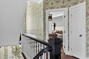 A staircase with a white railing leading to a bedroom with a bed and a nightstand. - Uptown Charlotte Luxury 4 bedroom Townhouse walkable to everything (Charlotte)