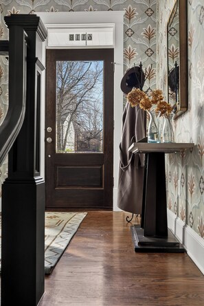 A wooden door with a dark frame, a small table with a vase of dried flowers, and a mirror on the wall. - Uptown Charlotte Luxury 4 bedroom Townhouse walkable to everything (Charlotte)