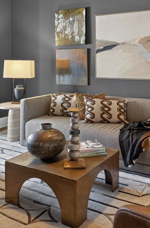 Un salon moderne avec un canapé, des coussins décoratifs, une table basse sur laquelle est posé un vase, et une lampe.
