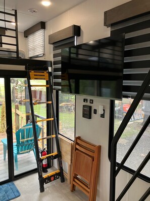 A room with a black and yellow ladder, a wooden bench, a window with blinds, and a control panel on the wall. - Beautiful 3-bedroom recreational vehicle with water view in Bronson (Bronson)