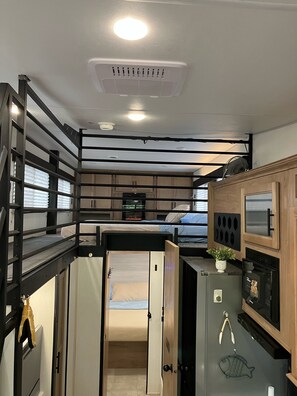 A compact RV interior with a kitchenette, a bed, and a small bathroom. - Beautiful 3-bedroom recreational vehicle with water view in Bronson (Bronson)