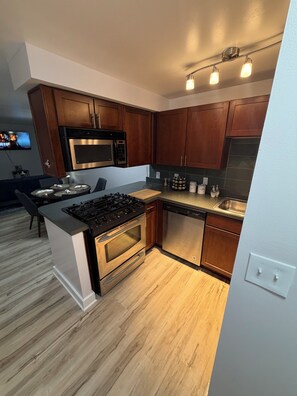 A modern kitchen with wooden cabinets, stainless steel appliances, and a central island.