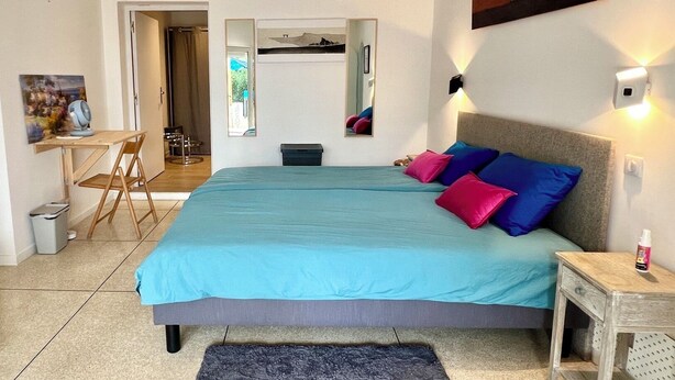 A bedroom with a bed, pillows, a desk, chair, and a small table. - Guesthouse with a pool, 200 meters from the beach, air-conditioned (Roquebrune-sur-Argens)