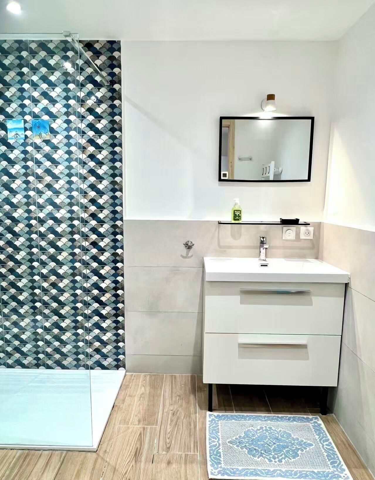A modern bathroom with a white vanity, a mirror, and a patterned shower curtain.