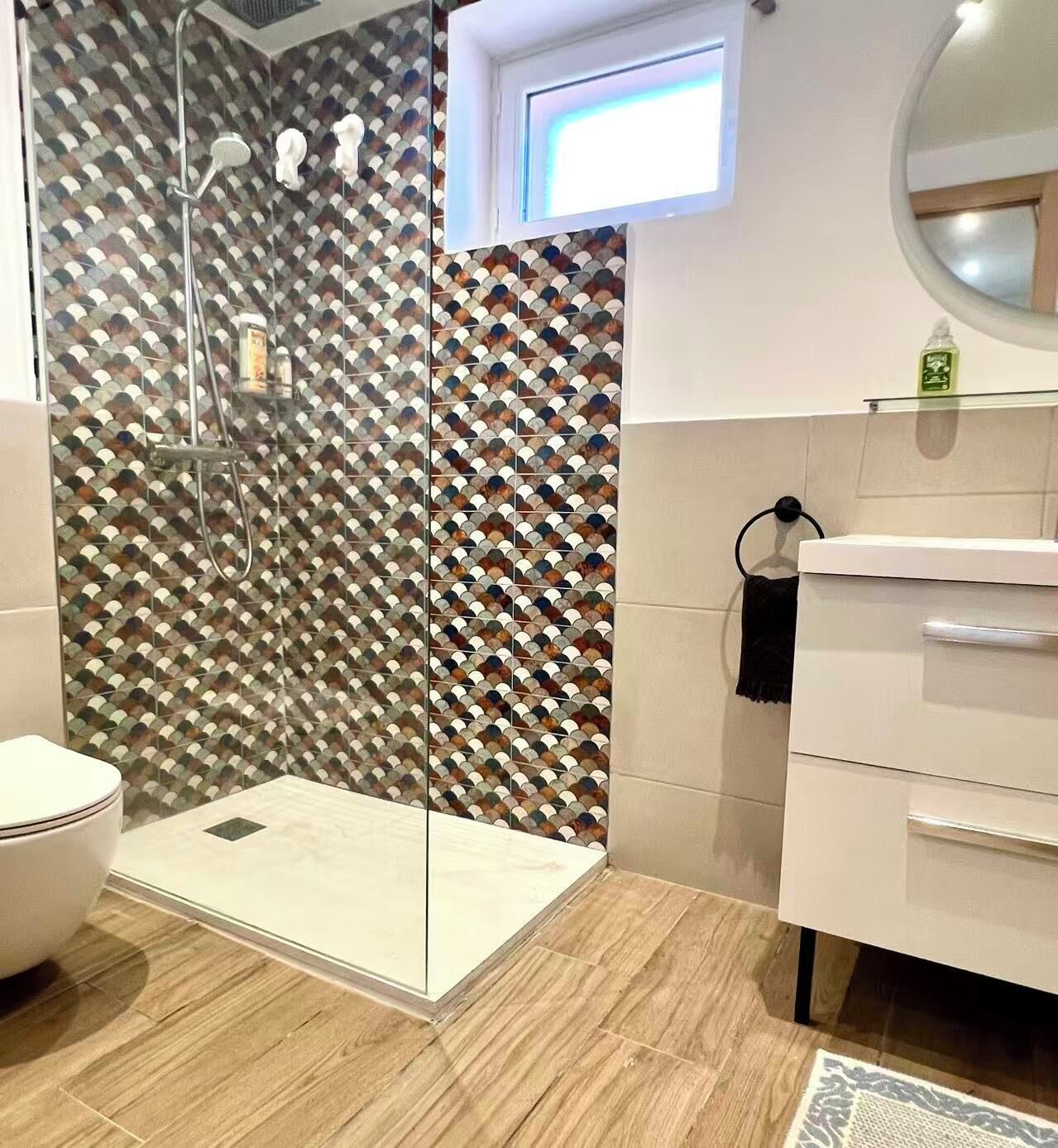 A modern bathroom with a shower enclosure, a toilet, and a vanity with a mirror.