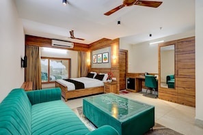 A modern hotel room with a bed, a sofa, a desk, and a mirror. - Deluxe Palette Hotel and Resort (Cuttack)