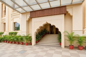 A building entrance with a staircase, potted plants, and a glass ceiling.