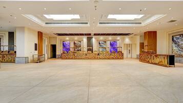 A spacious hotel lobby with a high ceiling, recessed lighting, and a central seating area with a decorative backdrop.