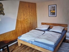 Una cama individual con cabecera de madera y cubierta de colchón azul en una habitación con suelo de madera y pared de paneles de madera.