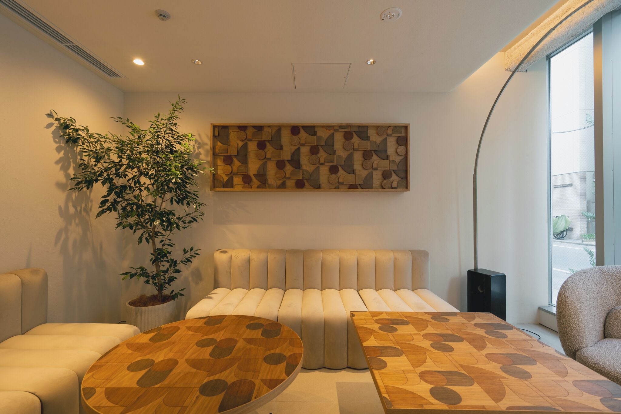 Une chambre d’hôtel moderne avec un grand lit, deux tables de chevet, une plante en pot et une œuvre d’art accrochée au mur.