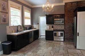 A modern kitchen with a central island, built-in appliances, and a chandelier.